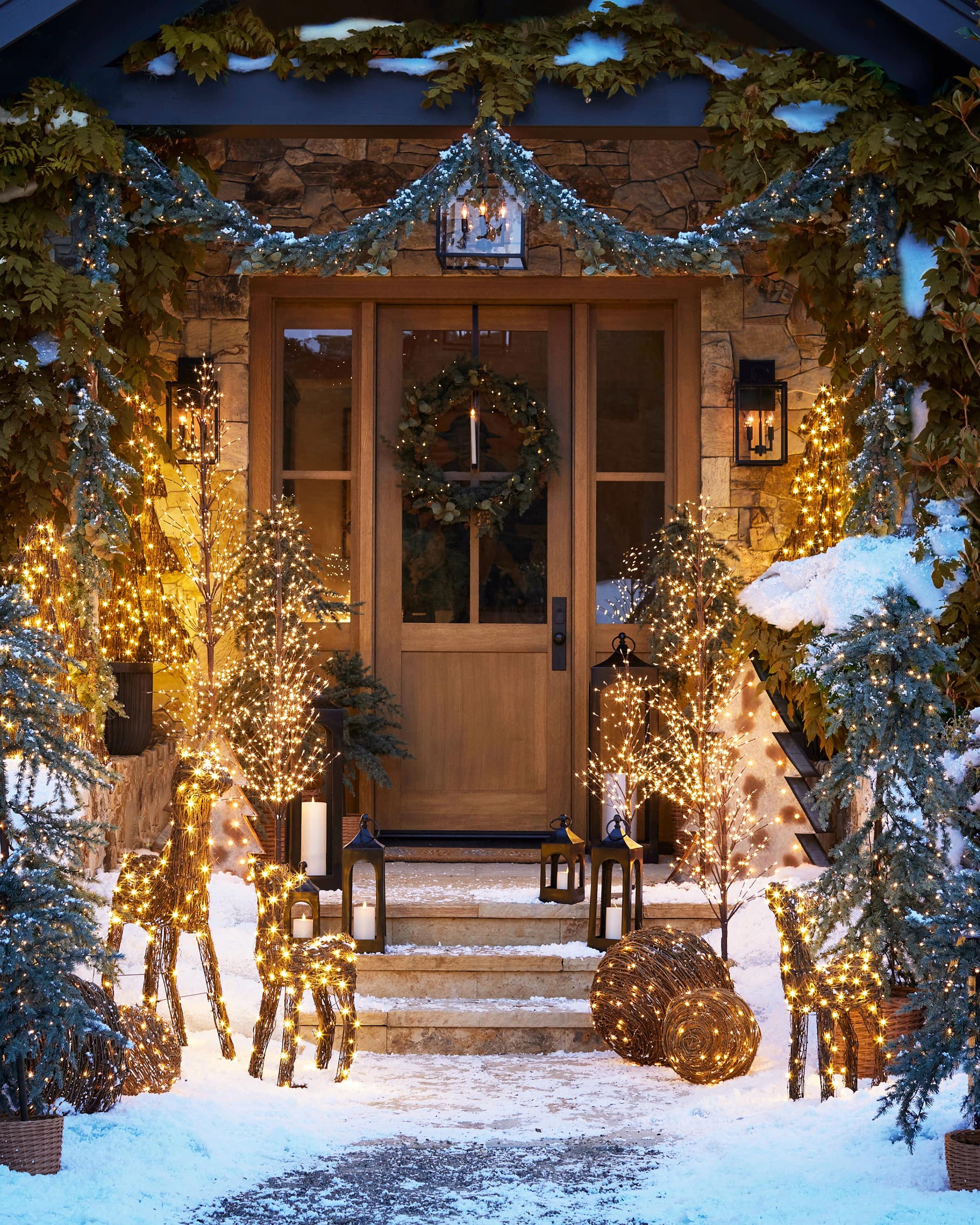 front door and steps decked out with lighted deer, balls, trees, candles, and garlands